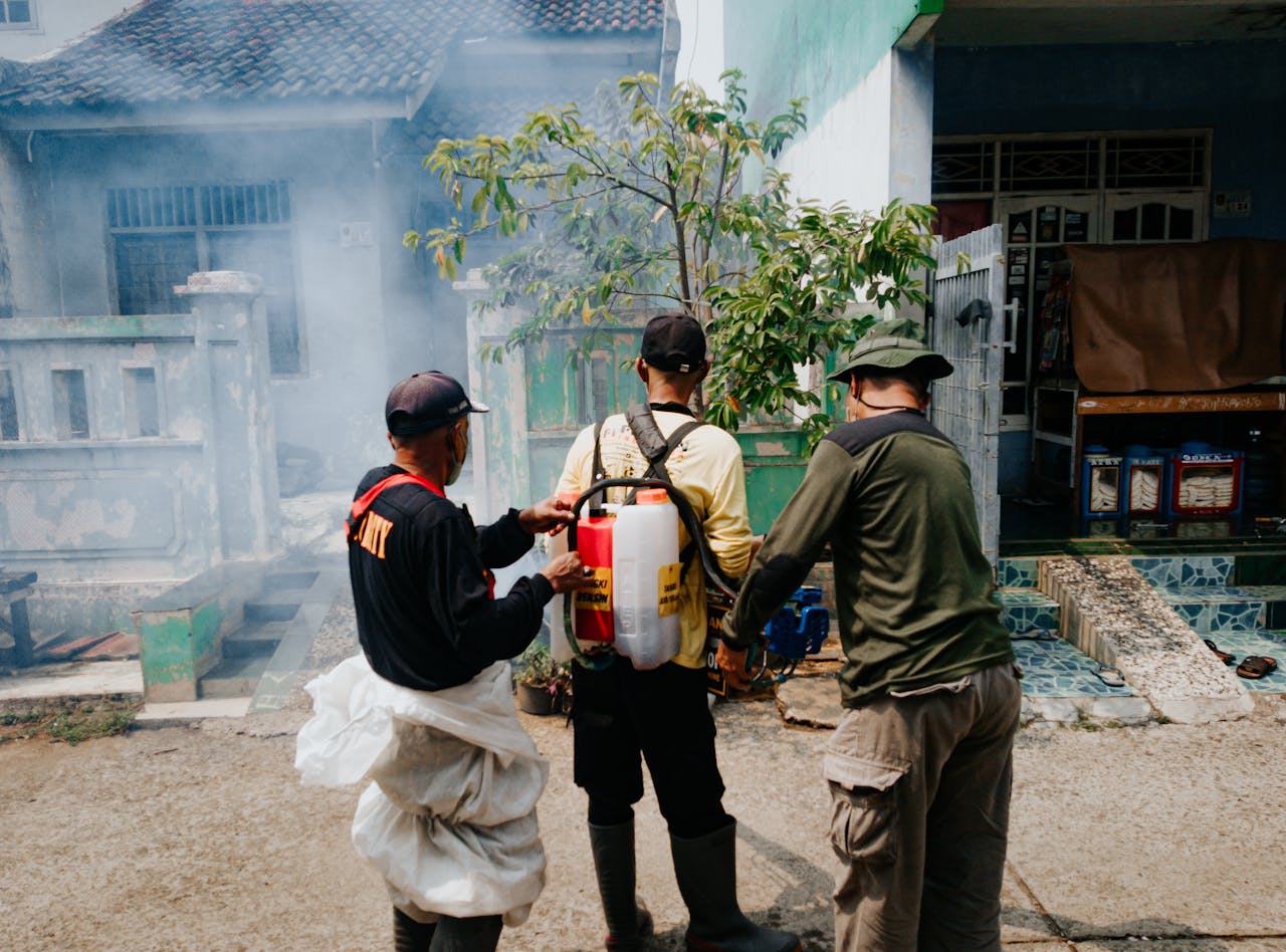Contact Three men engaged in street fumigation in Cibinong, Indonesia.