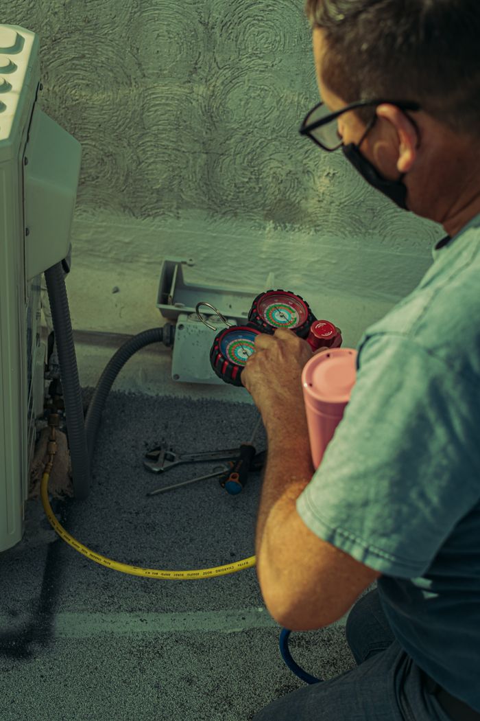 Services A technician checks and repairs an HVAC system outdoors using tools and gauges.
